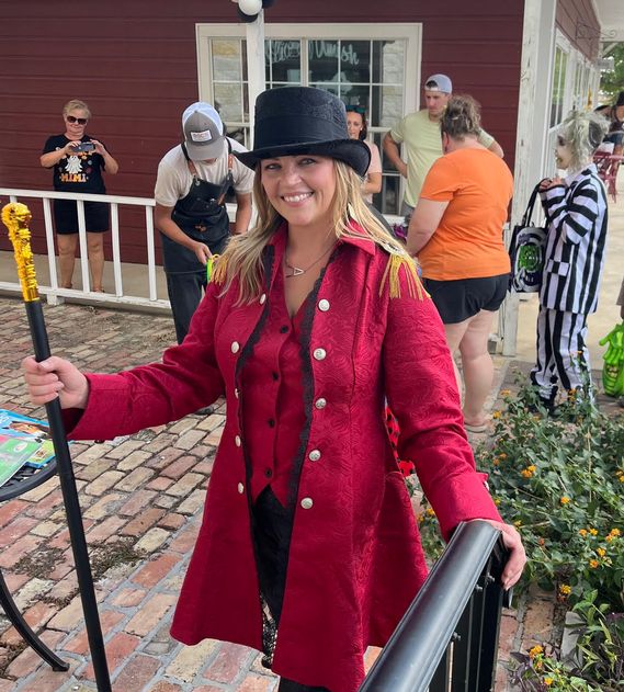 Slish of Amish general manager, and ringmaster Angie Miller, poses in front of her ring toss game with early Trick or Treaters